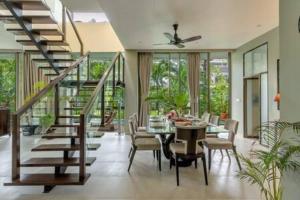 a dining room with a table and chairs and a staircase at sohonos · Luxurious 3bhk villa in Candolim in Goa