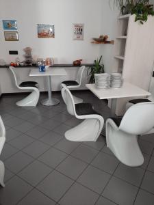 una sala da pranzo con tavoli e sedie bianchi di B&B Seventy Design a Dimaro