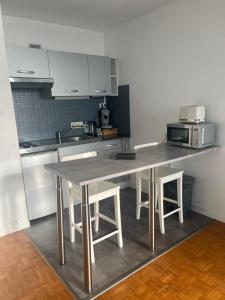 a kitchen with a table with chairs and a microwave at Vivez le Bonheur - Plage - Port de plaisance - Vue mer in Le Havre +10 photos