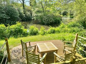 a wooden table and chairs on a wooden deck next to a river at Montgomery Barn in Bideford