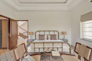 a bedroom with a bed and a table and chairs at Amananjuna 2 · Luxurious 5bhk villa in Anjuna in Goa +54 photos