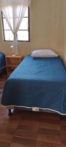 um quarto com uma cama azul e uma janela em The Hostal Elohim em Panajachel