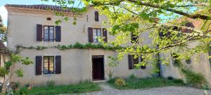 an old white house with black windows and trees at Haou de campagne in Peyre