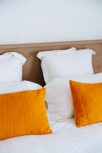 two white beds with orange pillows on them at Hôtel Casa Marina in Saintes-Maries-de-la-Mer