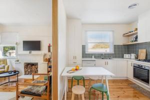 a kitchen with white cabinets and a table and chairs at Hazel House Ballarat in Wendouree