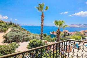 a balcony with a view of the ocean and palm trees at Amphora Hotel in Kaş