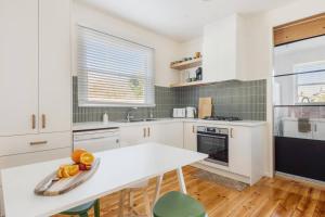 una cocina con armarios blancos y una mesa con fruta. en Hazel House Ballarat, en Wendouree