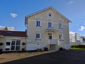 a white building with blue windows and a staircase at Le Jardin d Ambroise in Saint-Priest-en-Jarez