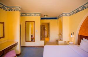 een slaapkamer met een wit bed en gele muren bij Marina Lodge at Port Ghalib in Port Ghalib