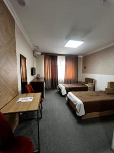 KökterekにあるАқ-жайық санаторийのベッド2台とテーブルが備わるホテルルームです。