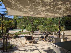 un patio con 2 sillas bajo una sombrilla grande en Provençal house between sea and vineyards, en Le Beausset
