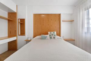 a bedroom with a large white bed with a wooden headboard at Apartamento Bellavista, bajo Alcalá in Guía de Isora