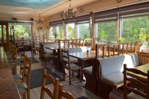 um restaurante com mesas e cadeiras de madeira e janelas em Hotel Restaurant Artemis em Willich