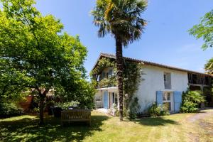 ein weißes Haus mit einer Palme und einer Bank in der Unterkunft Hautes Pyrénées Les Roses dAdour in Moulédous