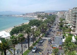 a busy city street with palm trees and the ocean at LE 5 CROISETTE OR in Cannes