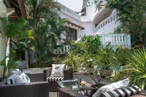 an outdoor patio with chairs and tables and plants at Villa Divina · Luxurious 4BHK Villa in Candolim in Goa
