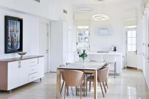 a white kitchen with a dining room table and chairs at Bauhaus Chic by HolyGuest in Tel Aviv