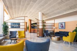 a lobby with yellow and blue chairs at htop Platja Park - Bliss in Platja d'Aro