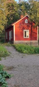 une grange rouge assise à côté d'une route en gravier dans l'établissement Charming Studio-Perfect Getaway, à Nummistenkylä