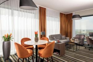 a living room with a table and chairs and a couch at Leonardo Royal Hotel Amsterdam in Amsterdam