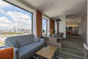 a living room with a couch and a large window at Leonardo Royal Hotel Amsterdam in Amsterdam