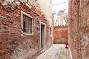 an alley with a red fire hydrant next to a brick building at Ca' Rosa Charming Suite Venice in Venice