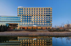 a large office building with a reflection in the water at Radisson Hotel, Beijing DaXing Airport in Beijing