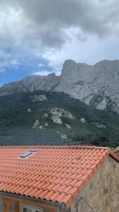 una casa con techo rojo con una montaña en el fondo en El Gallinero de Tiago, en Lebena