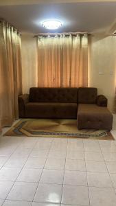 un soggiorno con divano marrone di fronte a una finestra di B&K Homestay Lahad Datu a Lahad Datu