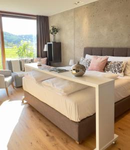 a bedroom with a large bed with a desk on it at Paradies in den Südsteirischen Weinbergen: Bezauberndes Apartment mit Terrasse, Infinity Pool-Zugang, Sauna und Fitnessbereich! in Obegg