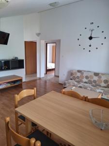 a living room with a table and a clock on the wall at Apartmani Romana in Punat