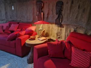 a living room with two red couches and a table at Original Maasai Lodge – Africa Amini Life in Ngare Nanyuki