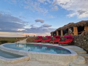 a swimming pool with red chairs and a building at Original Maasai Lodge – Africa Amini Life in Ngare Nanyuki