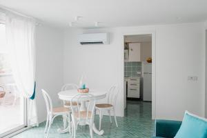 a white dining room with a white table and chairs at Villa Camilla by MyVillaCollection in Ischia +24 photos