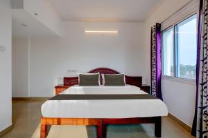 a bedroom with a large bed and a window at Super Collection O Tee Kay Near Railway Station in Chacka
