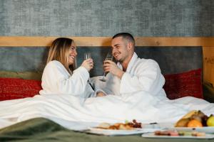 un hombre y una mujer sentados en la cama bebiendo vino en Hotel Verviers Van der Valk, en Verviers