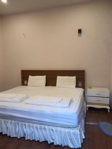 Bett mit weißer Bettwäsche und einem Kopfteil aus Holz in einem Zimmer in der Unterkunft Hotel ĐUC THANH VINH in Củ Chi