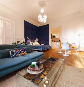 ein Wohnzimmer mit einem blauen Sofa und einem Tisch in der Unterkunft Le Carré Bleu - Studio Confort - Centre-ville in Dieppe