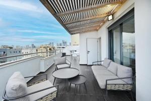 a balcony with a table and couches on a building at City View 2BR Duplex with MAMAD by HolyGuest in Tel Aviv