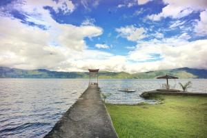 a dock with an umbrella and a boat on a lake at Hotel Pandu Lakeside Tuktuk in Tuktuk Siadong