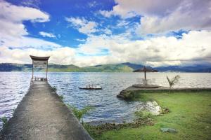 a dock with an umbrella in the middle of a lake at Hotel Pandu Lakeside Tuktuk in Tuk Tuk