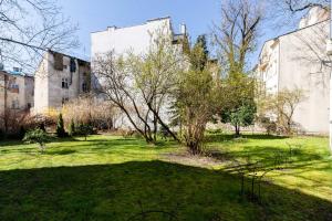 une cour verdoyante avec deux bâtiments et un arbre dans l'établissement Starowiślna 37 Apartment with Mezzanine, à Cracovie