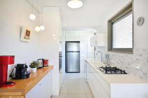 a kitchen with white counters and a stainless steel refrigerator at Smiling Joe by HolyGuest in Tel Aviv