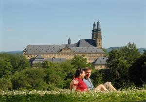 Un uomo e una donna seduti in un campo con un castello sullo sfondo di Best Western Plus Kurhotel an der Obermaintherme a Bad Staffelstein
