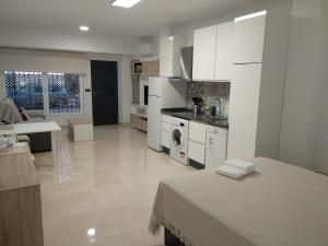 a white kitchen with a bed and a living room at Apartamentos Cordoba in Córdoba