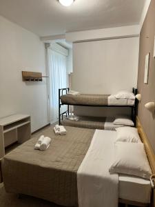 two beds in a room with towels on the bed at Hotel Enna Rimini in Rimini
