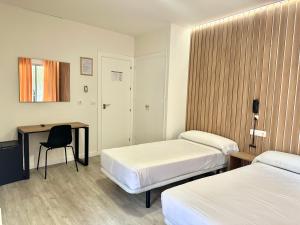 Cette chambre comprend deux lits, un bureau et une table. dans l'établissement Hotel Victoria Centro, à Almuñécar