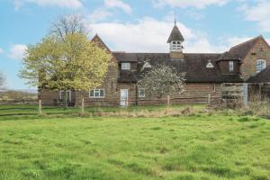 a large brick building with a tower on top of a field at The Coach House in Haywards Heath