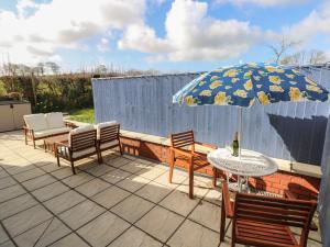 a patio with a table and chairs and an umbrella at The Annexe, Meadow Croft in Haverfordwest