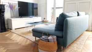 ein Wohnzimmer mit einem blauen Sofa und einem TV in der Unterkunft Le Carré Bleu - Studio Confort - Centre-ville in Dieppe